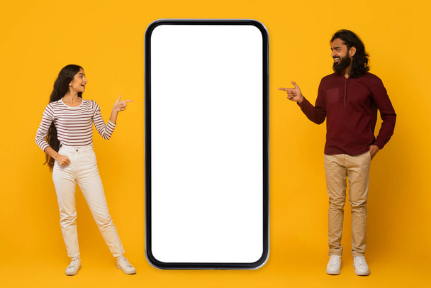 Man and woman interact with a large blank smartphone screen on a bright yellow background - Photo, Image