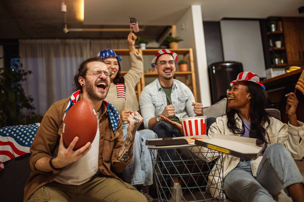 Multiracionális baráti társaság nézi rögbi amerikai zászlókkal. - Fotó, kép