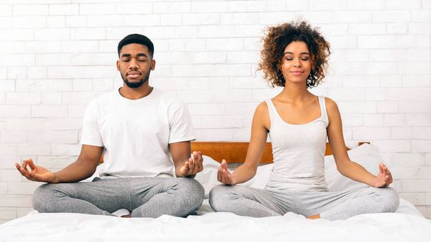 Um jovem e calmo casal afro-americano praticando meditação juntos em um ambiente sereno no quarto - Foto, Imagem