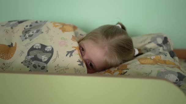 Sıcak battaniyeye sarılmış küçük bir kız gün boyunca uyur, huzur ve rahatlama ifade eder.. - Video, Çekim