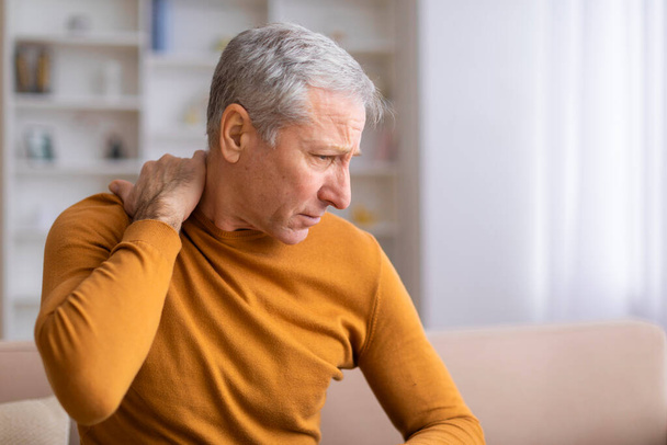Een oudere mannelijke persoon die last heeft van ongemak in zijn schouder, mogelijk een aanwijzing voor een gemeenschappelijke leeftijdsgebonden aandoening - Foto, afbeelding