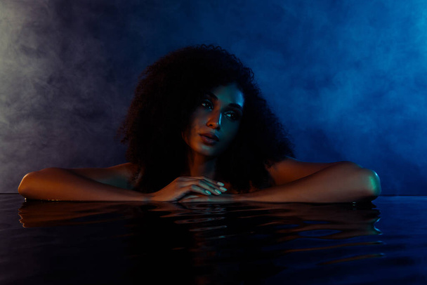 Photo de dame nue séduisante touchant l'eau passer le week-end au salon de spa relaxant dans la salle de bain bleue ultraviolette. - Photo, image