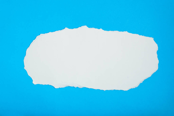 Torn white paper on blue paper background. Blank space for text. - Photo, Image