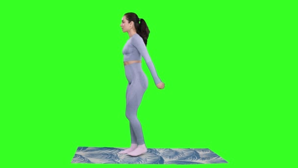 Sportovní mladá žena dělá dřepy cvičení, zatímco stojí na podložce jógy na zeleném izolovaném pozadí. Fitness, sport, zdravý, motivační koncept - Záběry, video
