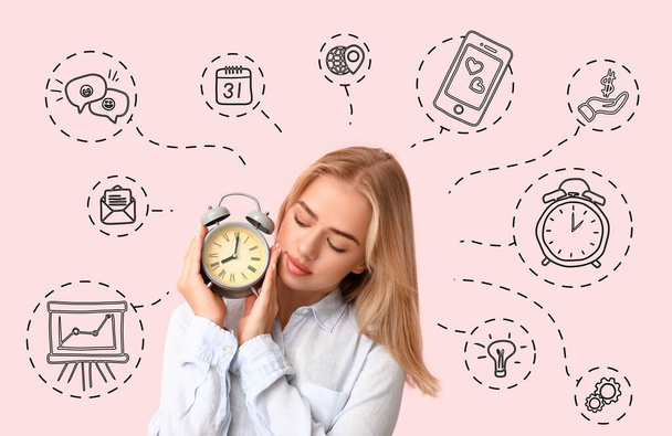 Young businesswoman with alarm clock on pink background. Time management concept - Photo, Image