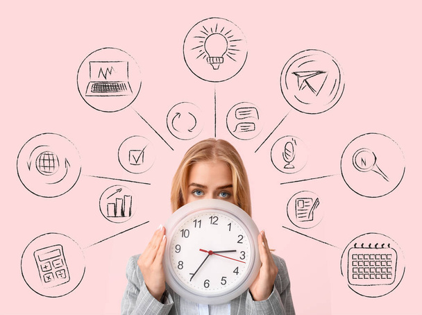 Junge Geschäftsfrau mit Uhr auf rosa Hintergrund. Zeitmanagement-Konzept - Foto, Bild
