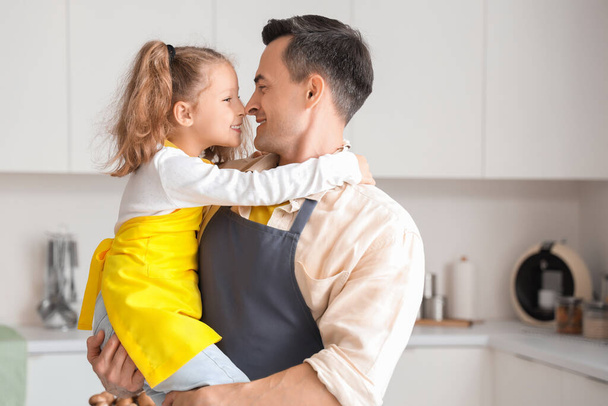 Χαριτωμένο κοριτσάκι με τον μπαμπά της να αγκαλιάζεται στην κουζίνα. - Φωτογραφία, εικόνα