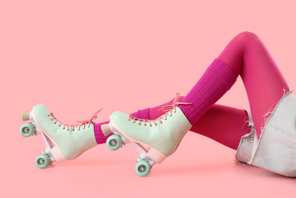 Ноги женщины в роликовых коньках на розовом фоне - Фото, изображение