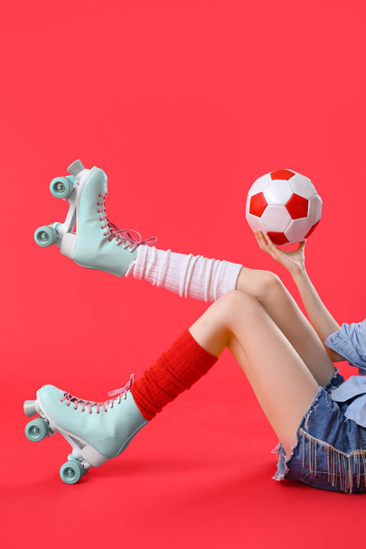 Vrouw in rolschaatsen met bal op rode achtergrond - Foto, afbeelding