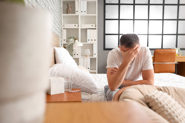 Мужчина средних лет страдает от головной боли в спальне - Фото, изображение