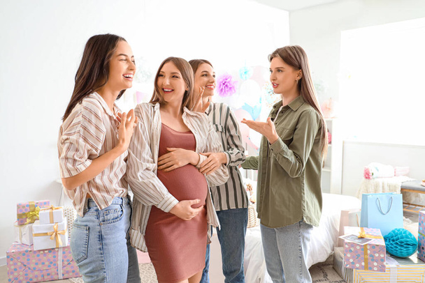Jovem mulher grávida com seus amigos conversando na festa do chá de bebê no quarto - Foto, Imagem