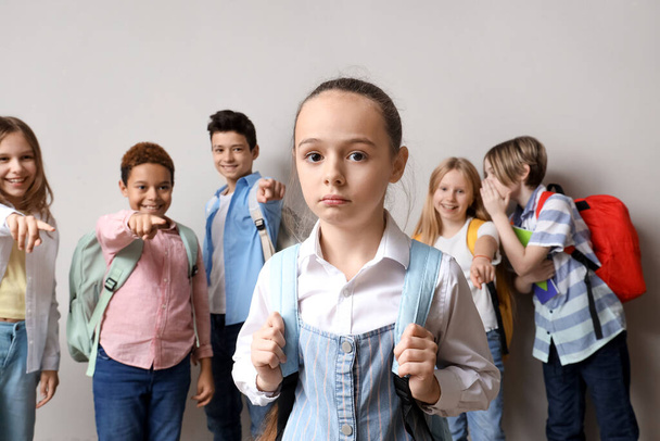 Bullied little girl and her classmates on light background - Photo, Image