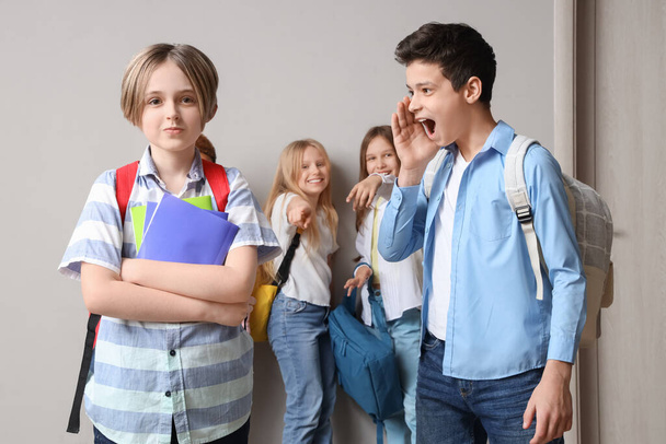 Šikanovaný chlapeček s učebnicemi a jeho spolužáky ve škole - Fotografie, Obrázek