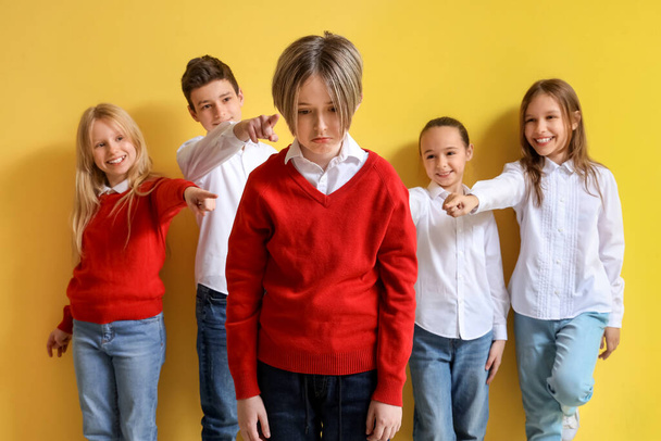 gepest kleine jongen en zijn klasgenoten op gele achtergrond - Foto, afbeelding