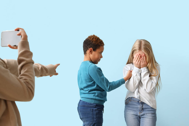Учні знущаються над маленькою дівчинкою на синьому фоні - Фото, зображення