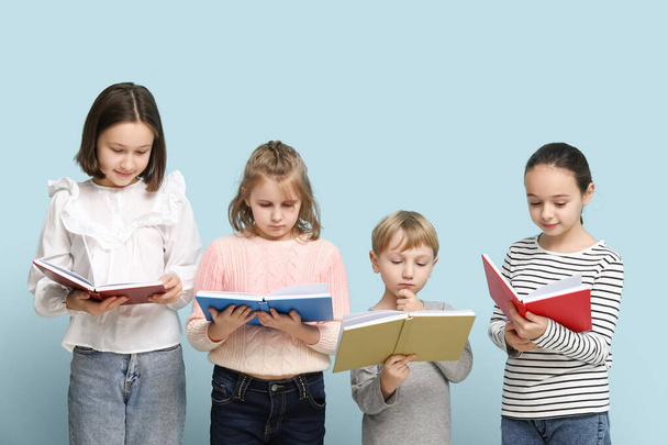 青い背景の本を読んでいる小さな子供たち - 写真・画像