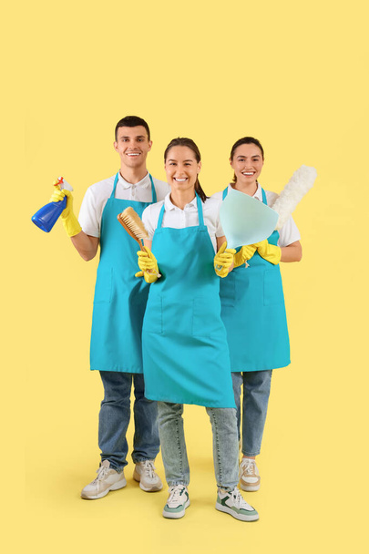 Trabajadores del servicio de limpieza con suministros sobre fondo amarillo - Foto, imagen