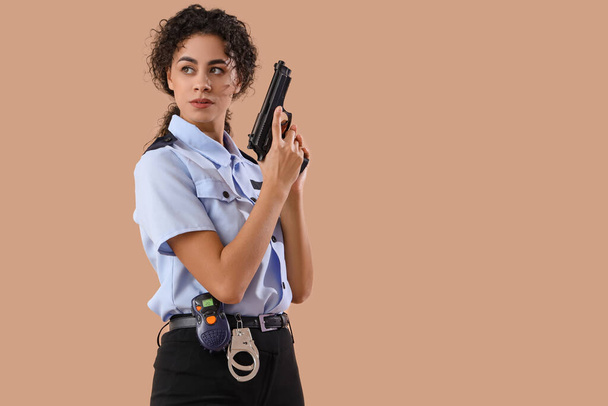 アフリカ系アメリカ人女性警察官,茶色の背景に銃を所持 - 写真・画像