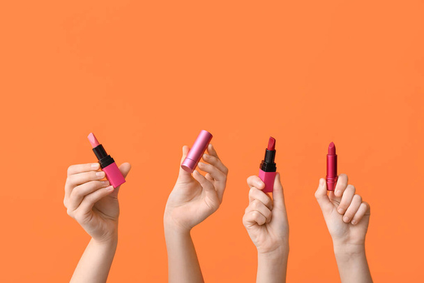 Female hands with lipsticks on orange background - Photo, Image