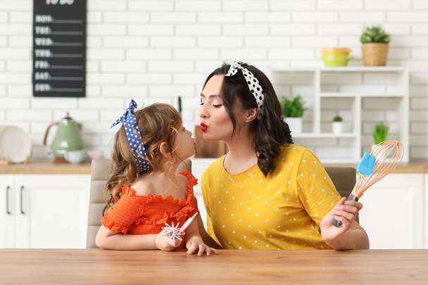 Hermosa mujer pin-up y su hija con utensilios de cocina en la cocina - Foto, imagen