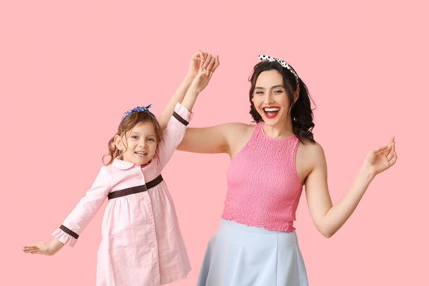 Όμορφη γυναίκα με καρφίτσα και η κόρη της σε ροζ φόντο - Φωτογραφία, εικόνα