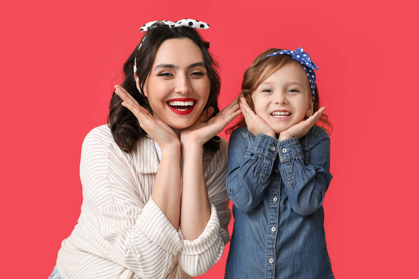 Beautiful pin-up woman and her daughter on red background - Photo, Image