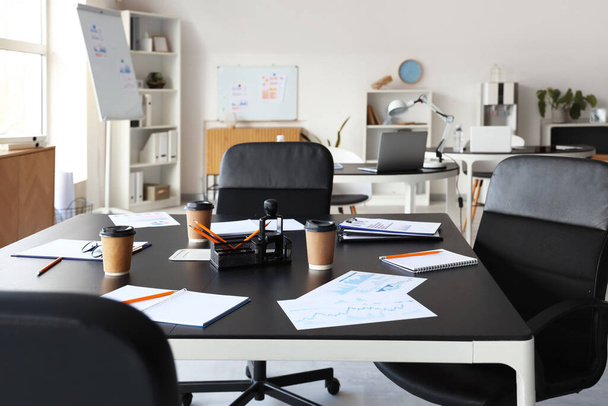 Pöytä, jossa on paperia, nojatuoleja ja johtokuntia ja joka on valmisteltu kokoussalissa pidettävää liikekokousta varten - Valokuva, kuva