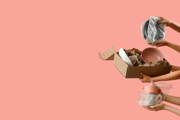 Женщины с движущейся коробкой и кухонной посудой на розовом фоне - Фото, изображение