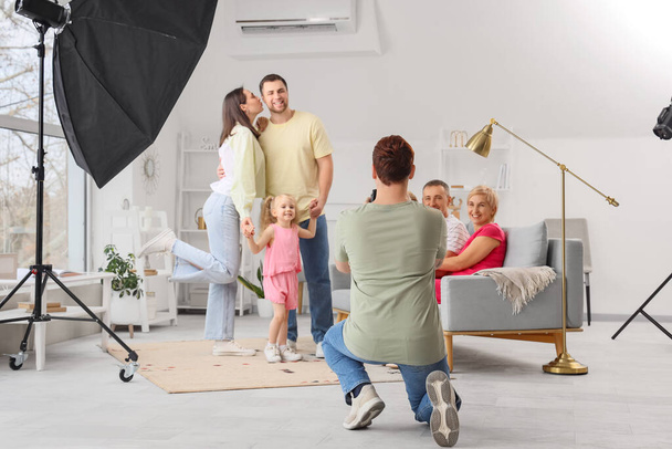 Чоловік фотограф фотографує велику сім'ю в студії, вид ззаду - Фото, зображення
