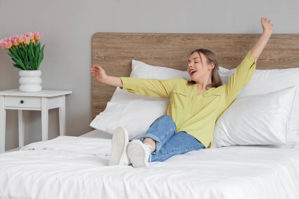 Rahatlamış genç bir kadın yatak odasında rahat bir yatakta yatıyor. - Fotoğraf, Görsel