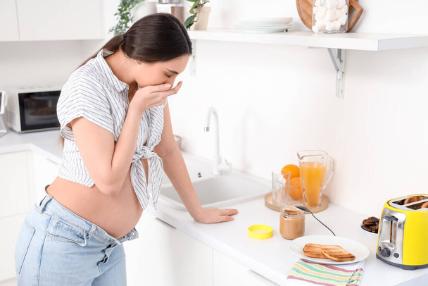 Nuori raskaana oleva nainen kärsii toxicosis keittiössä
 - Valokuva, kuva