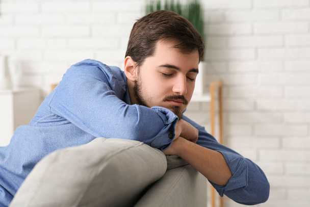 Unavený mladý muž sedí doma na gauči, detailní záběr - Fotografie, Obrázek