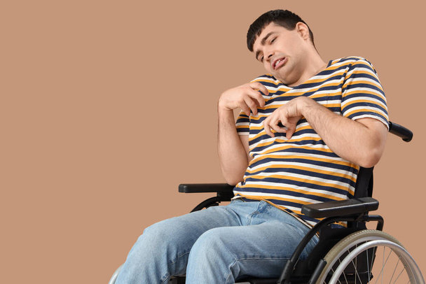 Young man in wheelchair on brown background. National Cerebral Palsy Awareness Month - Photo, Image