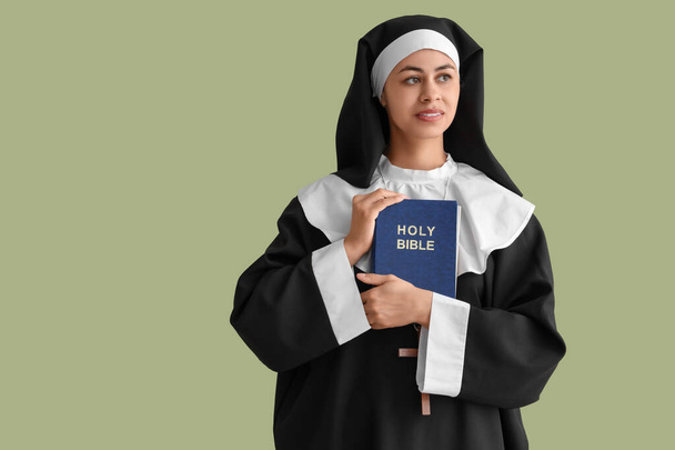Νεαρή καλόγρια με τη Βίβλο στο πράσινο φόντο - Φωτογραφία, εικόνα