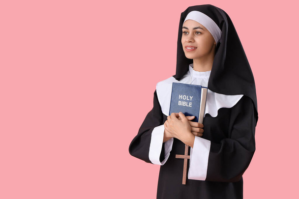 Junge Nonne mit Bibel auf rosa Hintergrund - Foto, Bild