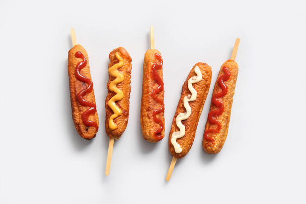 Tasty corn dogs with different sauces on grey background - Photo, Image