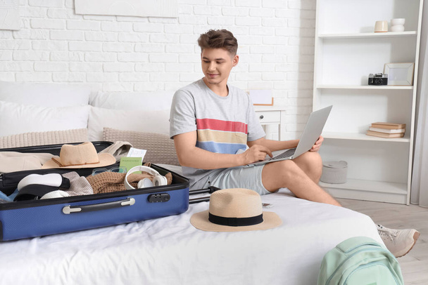 Мужской турист с чемоданом с ноутбуком в номере отеля - Фото, изображение