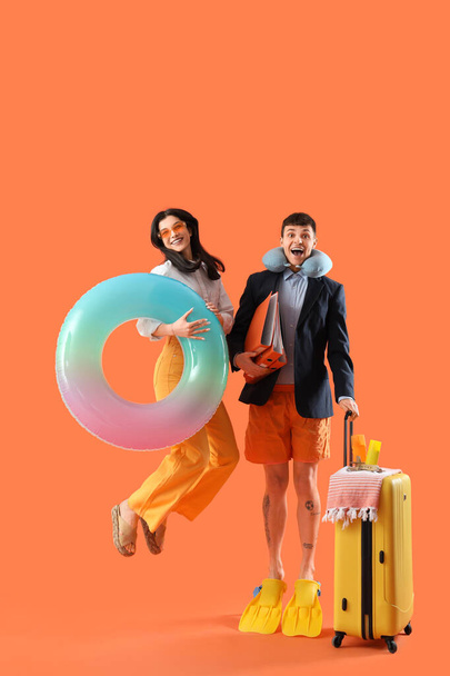 Compañeros de negocios con carpetas y accesorios de playa listos para las vacaciones de verano sobre fondo naranja - Foto, imagen