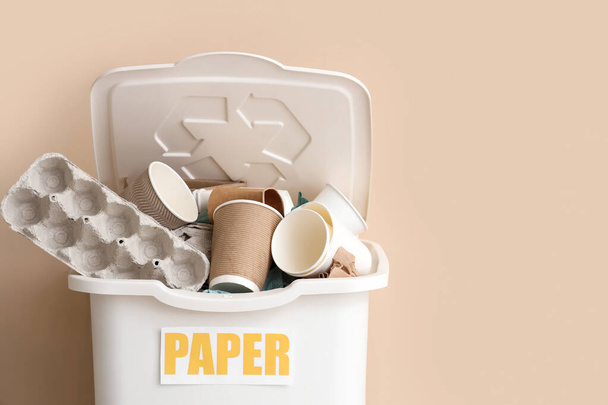 Poubelle de recyclage blanche avec litière en papier près du mur beige. Concept de recyclage - Photo, image