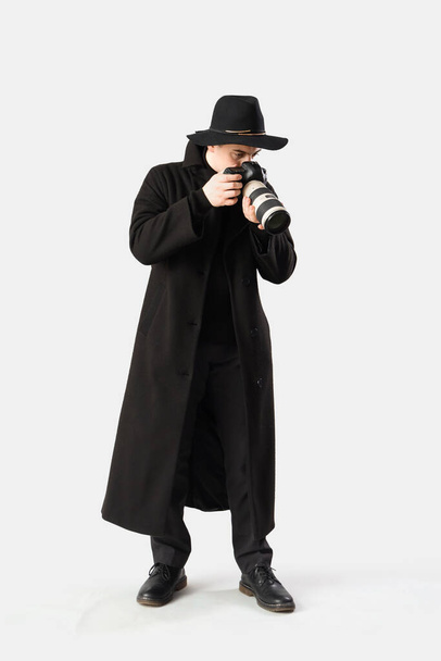 Espía masculino con cámara fotográfica sobre fondo claro - Foto, Imagen