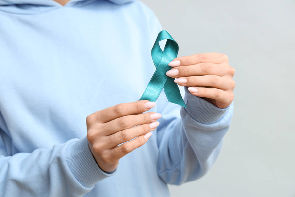Young woman with teal ribbon on grey background, closeup. Sexual Assault Awareness Month - Photo, Image