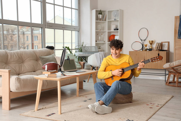 Étudiant masculin jouant de la guitare en streaming à la maison - Photo, image