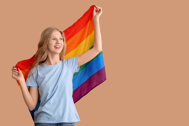 Belle jeune femme heureuse avec drapeau LGBT sur fond beige - Photo, image