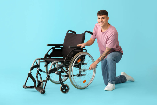 Komea nuori onnellinen mies jakoavaimella korjaus pyörätuoli sinisellä pohjalla - Valokuva, kuva