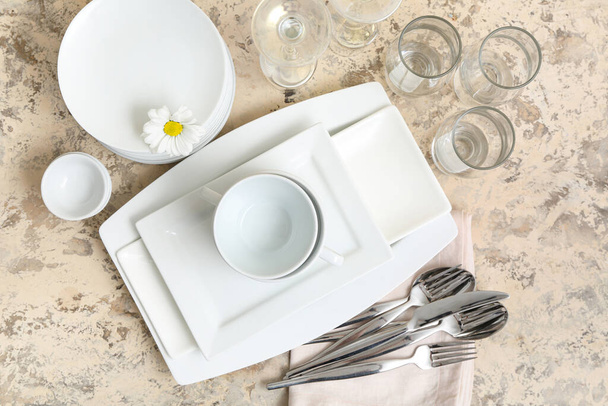 Composition with clean dishes, chamomile, glasses and cutlery on light background - Photo, Image