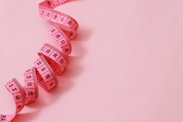 ruban à mesurer pour les personnes obèses sur un fond rose soft focus - Photo, image