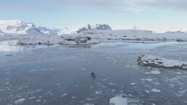 La gente en el barco a motor inflable de goma navega en el hielo antártico a la estación polar de Akademik Vernadsky. Rastreando vista aérea. Transporte Expedición Explorando Agua Fría Extrema. Drone. - Foto, imagen