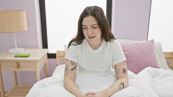 Veselá mladá žena v pyžamu vítězoslavně bliká radostným gestem vzhůru z postele, vyzařuje pozitivitu ve své ložnici - Záběry, video