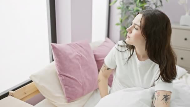 Happy young woman in pyjama, confidently searching the distance, hand-held high, looking away from bed in room's indoor space - Footage, Video