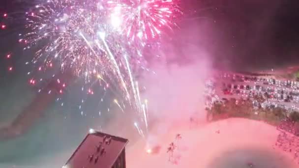 Беспилотник летит над красочными сверкающими фейерверками, взрывающимися ночью. Фейерверки взрываются в небе на курортах Вайкики. Туристы привлекают на острове Оаху Гавайи. Люди празднуют жизнь на летних каникулах - Кадры, видео